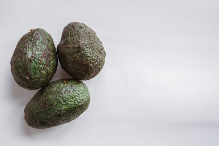 Top view of similar fresh exotic avocados with rough dry peel on table at home