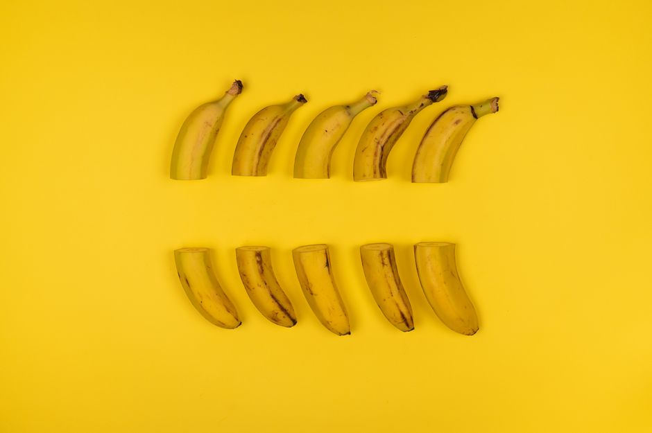 Creative composition of sliced bananas arranged on a vivid yellow surface.